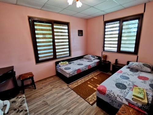 2 camas en una habitación con paredes y ventanas de color rosa en Guest House Kosharite en Byala Ruse