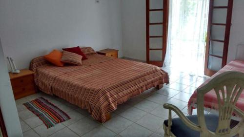 a bedroom with a bed and a chair and a window at Viver Ubatuba in Ubatuba