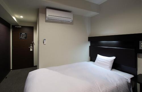 a bedroom with a white bed with a black headboard at Green Rich Hotel Yamaguchi Yuda Onsen in Yamaguchi