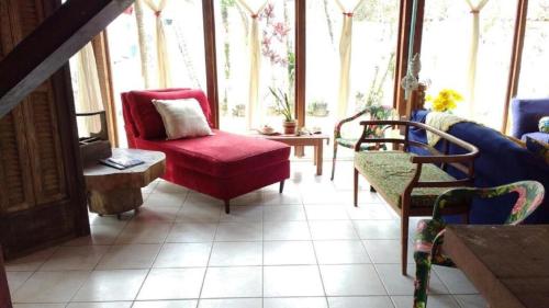 una sala de estar con una silla roja y ventanas en Viver Ubatuba, en Ubatuba