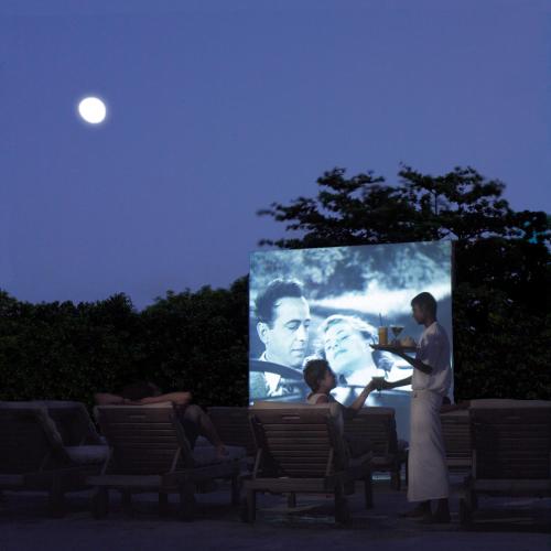 a woman standing in front of a movie screen at Soneva Fushi in Baa Atoll