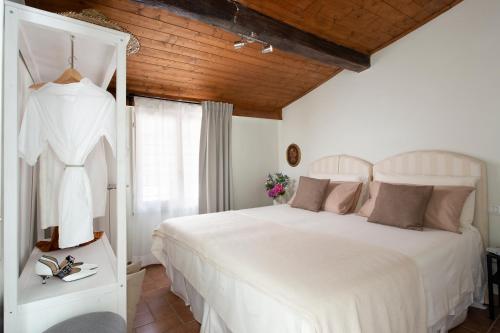 Scacciapensieri Guest House في أريتسو: غرفة نوم بسرير ابيض وسقف خشبي
