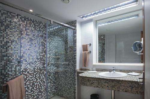 y baño con lavabo y ducha con espejo. en Hotel Riu Monica - Adults Only, en Nerja