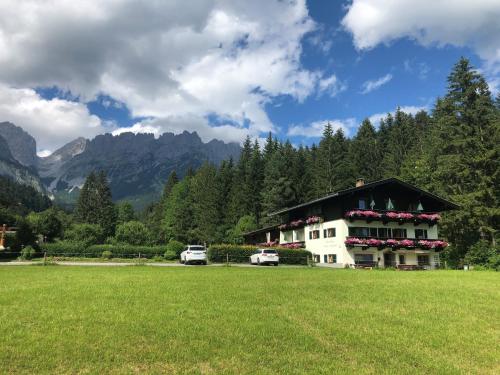 a house with two cars parked in a field at otto steiner appartements pension ellmau & wilder kaiser in Ellmau