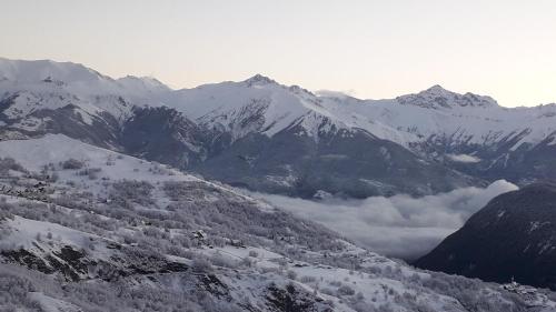 Studio 4 personnes au pied des pistes في لي كوربيه: سلسلة جبلية مغطاة بالثلوج مع وجود الغيوم في الوادي