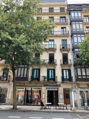 a building on a street with a tree in front of it at Pensión Urkia in Donostia-San Sebastián