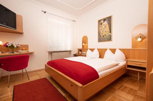 a bedroom with a large bed with a red blanket at Hotel Liebetegger-Klagenfurt in Klagenfurt