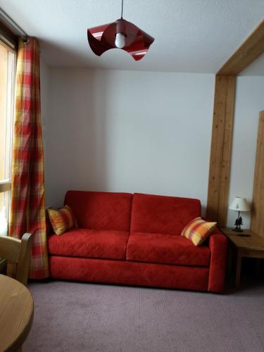 a red couch in a living room with a ceiling at Résidence Le Chamois d'Or in Val Thorens