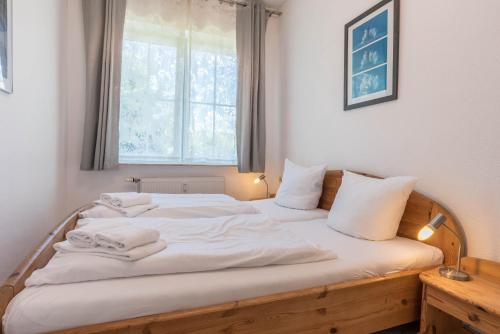 - une chambre avec un lit doté de draps blancs et une fenêtre dans l'établissement Cottage am Watt, à Nebel