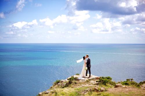 a bride and groom standing on top of a cliff at The Atlantic Hotel - Small Luxury Hotels of the World in St Brelade