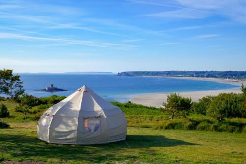 a white tent sitting on top of a field next to a beach at The Atlantic Hotel - Small Luxury Hotels of the World in St Brelade
