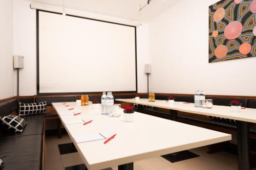 a row of tables in a room with a large screen at Hotel Liebetegger-Klagenfurt in Klagenfurt