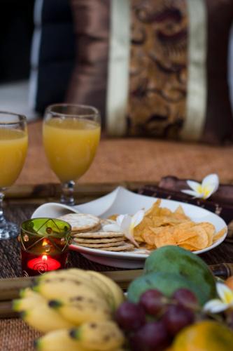ein Tisch mit einem Teller Essen und zwei Gläsern Orangensaft in der Unterkunft Villa Savannah in Canggu