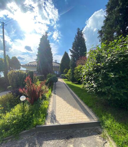 a brick walkway in a yard with bushes and trees at Zajazd Maj in Bolesław