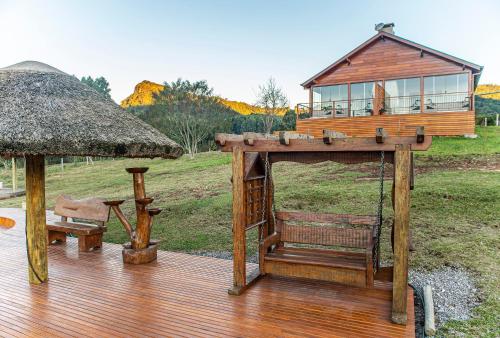 una terraza de madera con una casa y una silla en BANGALÔS REFÚGIO DO VALE, en Santa Maria do Erval