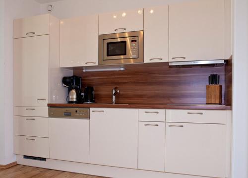 cocina con armarios blancos y microondas en Lux Alpinae, en Nauders