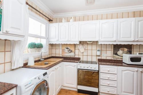 a kitchen with white cabinets and a dishwasher at Anima in Can Picafort