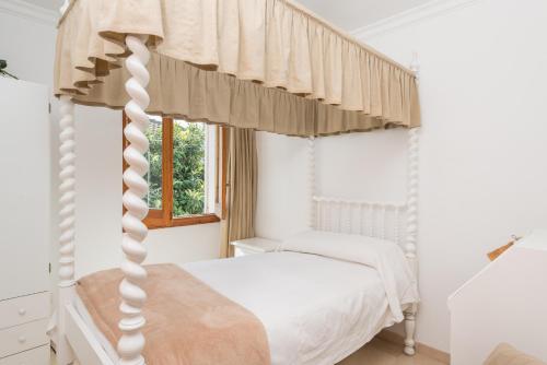 a bedroom with a white canopy bed with a window at Anima in Can Picafort