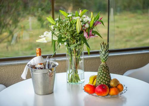 Santa Maria do ErvalにあるBANGALÔS REFÚGIO DO VALEの花瓶一皿と果物一皿