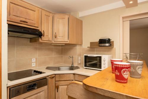 a kitchen with wooden cabinets and a counter top at Résidence Le Chamois d'Or in Val Thorens