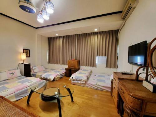 um quarto com 4 camas e uma televisão de ecrã plano em Xincun Seed Homestay em Anping