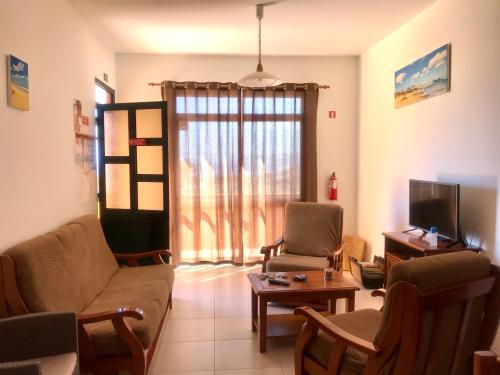 een woonkamer met een bank en stoelen en een tv bij Cantinho Solpraia in Porto Santo