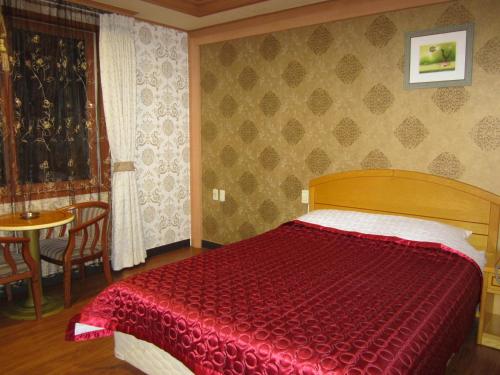 a bedroom with a red bed and a table at Jeju Olleh Hotel in Jeju