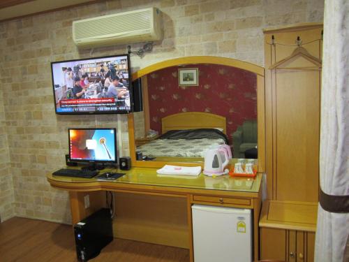 a bedroom with a desk with a computer and a bed at Jeju Olleh Hotel in Jeju