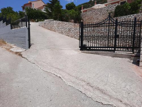 a driveway with a black gate and a stone wall at Freesia Grand Sea View Residence in Sarlata