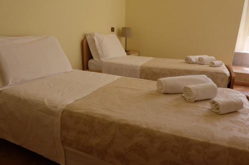 Dos camas en una habitación de hotel con toallas. en Hostel il Tetto, en Melfi