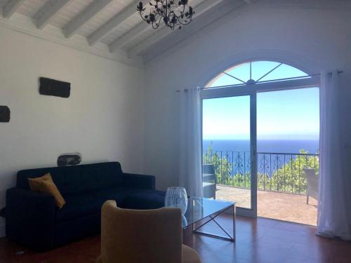 un soggiorno con divano blu e vista sull'oceano di La VIGIE de CASTELROCK ( Casa Petunia ) a Mosteiros