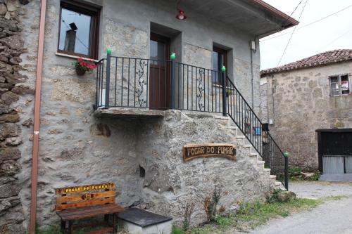 ein Steingebäude mit einer Bank und einem Balkon in der Unterkunft Fogar do Pumar in Pantón