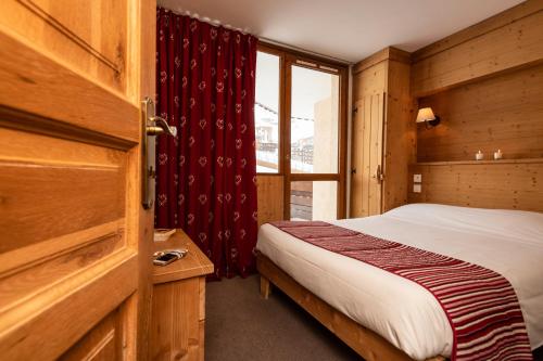 een kleine slaapkamer met een bed en een raam bij Résidence Le Chamois d'Or in Val Thorens