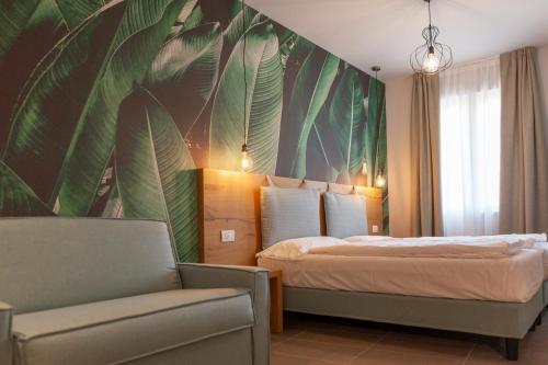 een slaapkamer met een bed met een grote muurschildering van bladeren bij epOche Hotel Zanella 1889 in Nago-Torbole
