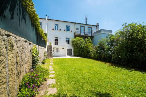 a large white house with a grass yard at Beach Golf & Garden House in Arcozelo