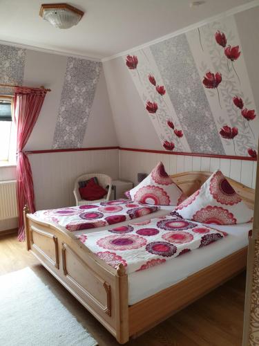 a bedroom with a bed with red flowers on the wall at Pension To olen Slüüs Dagebüll in Dagebüll