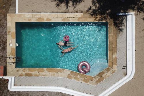 two people swimming in a swimming pool with a pool at Made iN2 Creative Guest House in Montargil