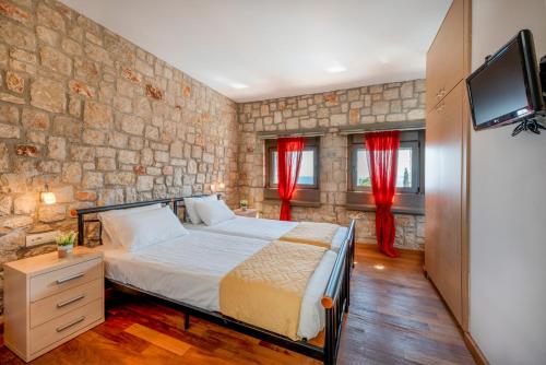 a bedroom with a bed with red curtains and a tv at Villa CostaMare - enjoy lazy days on the private Pool-Jacuzzi in Pefki Rhodes