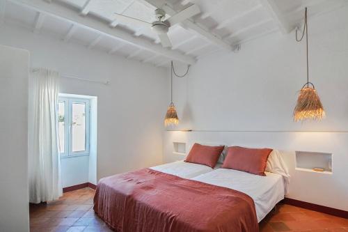 a white bedroom with a bed with red pillows at Agroturismo Bini Aumaia in Es Mercadal