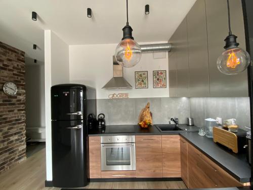 La cuisine est équipée d'un réfrigérateur noir et d'un évier. dans l'établissement Apartament DeLux przy Wiśle, à Cracovie