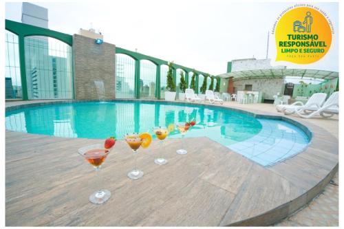 a group of martini glasses sitting on a table near a swimming pool at Hotel Nacional Inn Curitiba Estação Shopping in Curitiba