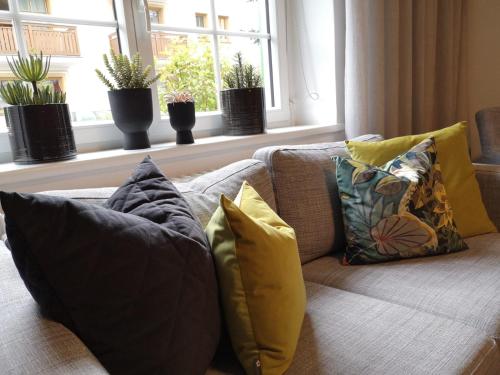 a living room with a couch with pillows and a window at Seehotel Sissi in Zell am See