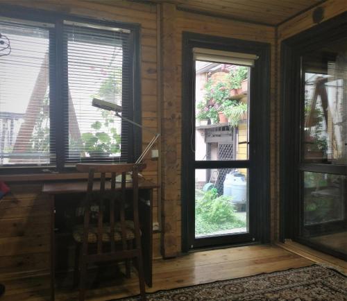 Cette chambre dispose de deux fenêtres et d'un fauteuil en bois. dans l'établissement Деревянный 2-х комнатный домик, à Kiev