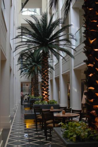 a hallway with two palm trees in a building at The Lalit Great Eastern Kolkata in Kolkata