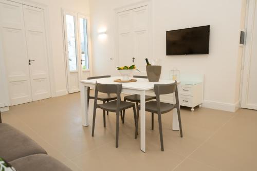 biały stół jadalny z krzesłami i telewizor w obiekcie Corte Sant'Angelo w mieście Monopoli