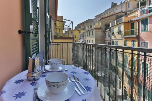 a table with two cups and saucers on a balcony at CATEO in Riomaggiore