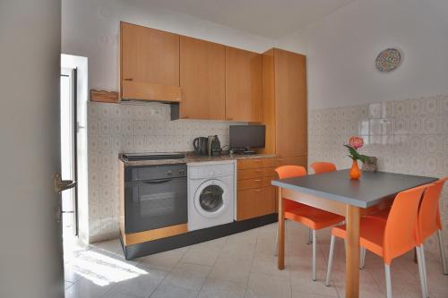 uma cozinha com uma máquina de lavar roupa e uma mesa com cadeiras laranja em CATEO em Riomaggiore