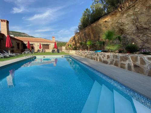 a swimming pool with blue water in front of a house at Hotel Rural La Cabrera in Robledo del Buey