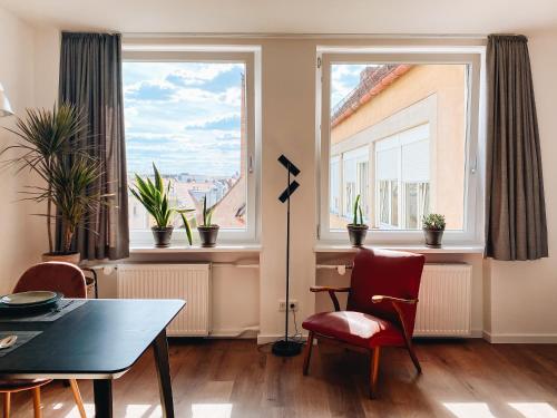 a living room with a table and chairs and two windows at Lorenz Apartments in Nürnberg