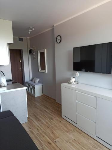 a white kitchen with a large tv on the wall at Apartament New Slavia in Międzyzdroje